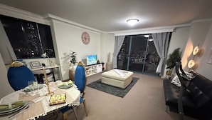 A dining area with a table set for four, a sofa, and a view of the city at night.