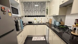 A modern kitchen with white cabinets, a black countertop, and a tiled floor.