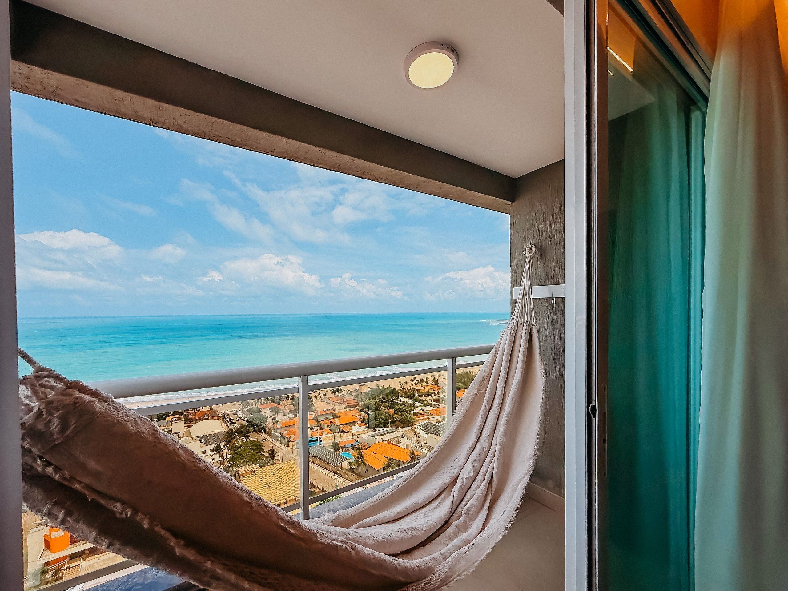 Een balkon met uitzicht op de oceaan en een hangmat.