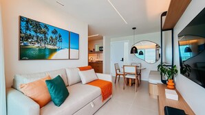 A modern living room with a sofa, a dining area with a table and chairs, a kitchen in the background, and a large window. - Ahead Ponta Negra by Almare (Natal)