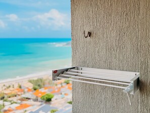 A metal rack attached to a textured wall, overlooking a coastal view with buildings and a clear sky. - Ahead Ponta Negra by Almare (Natal)