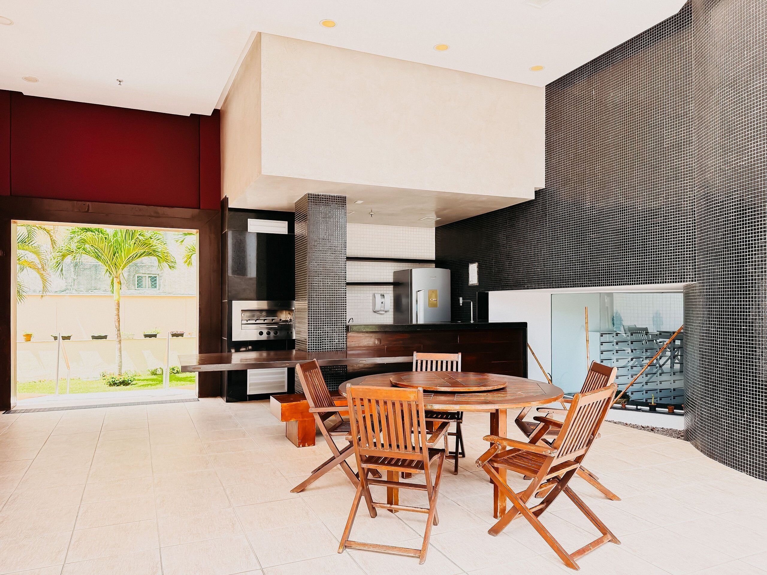 A modern kitchen with a central island, built-in appliances, and a large window overlooking a garden.
