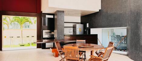 A modern kitchen with a central island, built-in appliances, and a large window overlooking a garden.