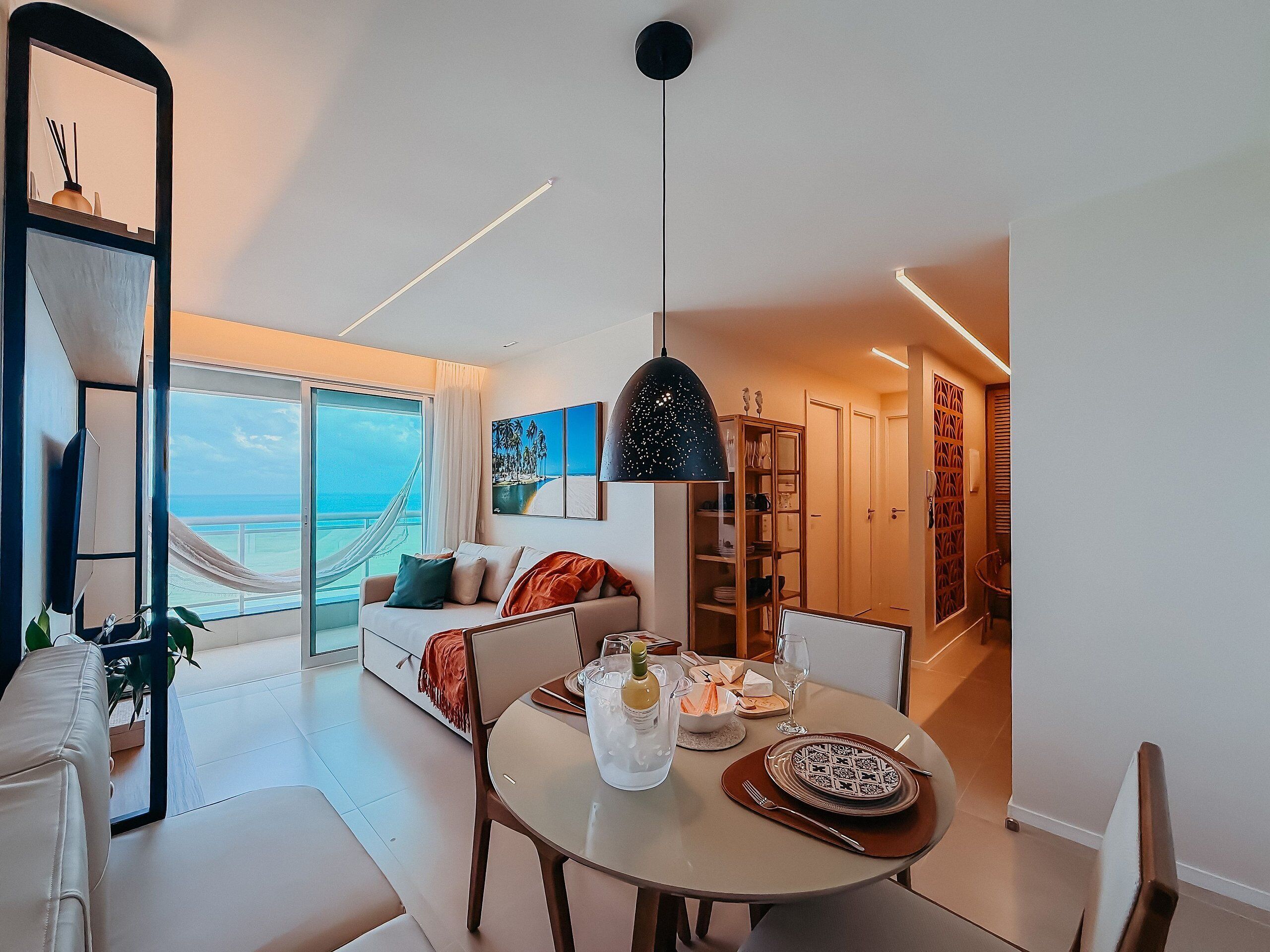 Une chambre d’hôtel moderne avec balcon, coin repas et vue sur la mer.