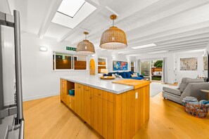 A modern kitchen with wooden cabinets, a central island, and pendant lighting. - 25% Off Nov 5-8, Walk To Beach, Roof-Top Patio! (Oxnard)