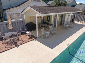 A covered outdoor patio with a pool, featuring a barbecue grill, outdoor furniture, and a small covered seating area. - Private Home l 5 min Walk to Beach l 3BR l Pool (North Myrtle Beach)