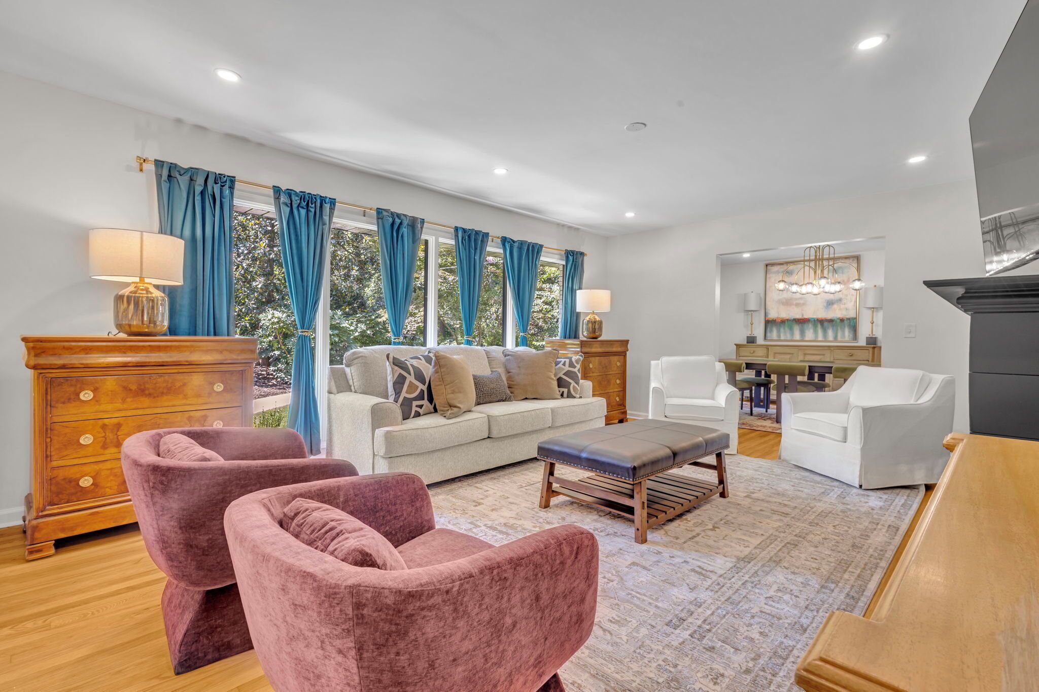A living room with a sofa, two armchairs, a coffee table, and a dining area with chairs and a table.