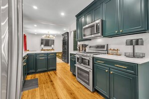 A modern kitchen with dark cabinetry, stainless steel appliances, and a wooden floor. - Buckhead Hideaway ~ 4BR, Fire Pit, Big Deck! (Atlanta)