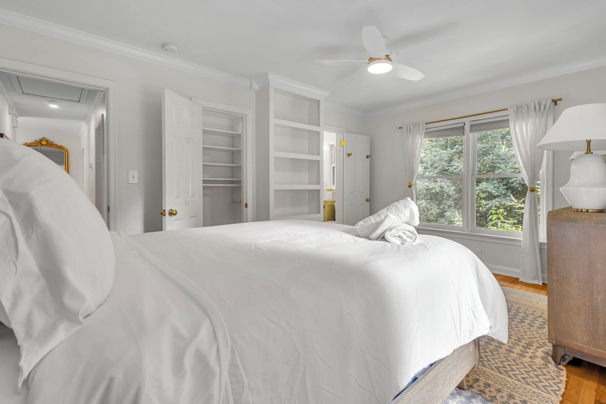 A bedroom with a large bed, built-in closet, and a window with curtains.