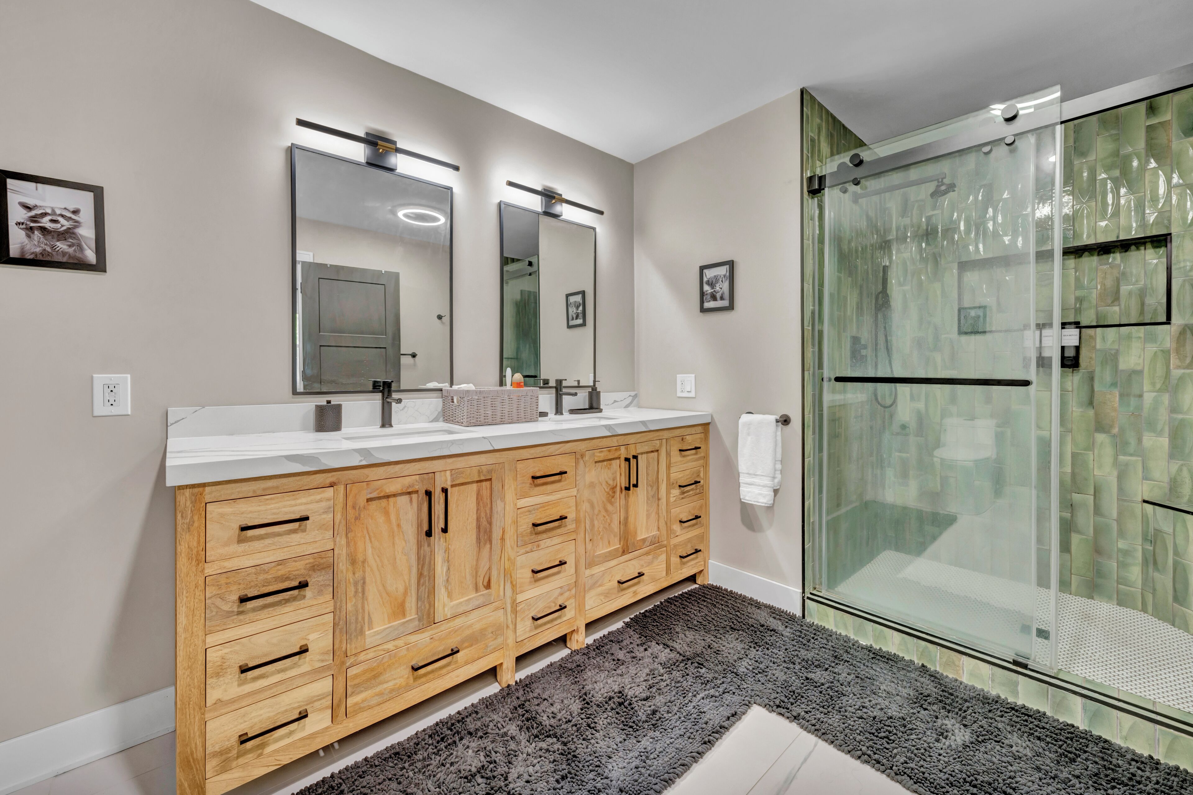 A modern bathroom with a wooden vanity, a glass shower enclosure, and a large mirror.