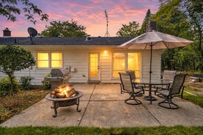 Een huis met een terras, buitenmeubilair, een vuurkorf en een schotelantenne.