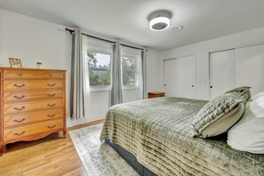 A bedroom with a bed, dresser, and two doors. - The Spartan Ranch (East Lansing)
