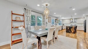 A modern kitchen with a central island, wooden flooring, and a dining area with a chandelier. - The Spartan Ranch (East Lansing)
