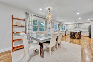 A modern kitchen with a central island, wooden flooring, and a dining area with a chandelier. - The Spartan Ranch (East Lansing)