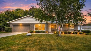 A residential house with a garage, a front porch, and a well-maintained lawn. - The Spartan Ranch (East Lansing)