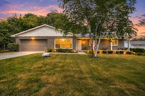 A residential house with a garage, a front porch, and a well-maintained lawn. - The Spartan Ranch (East Lansing)