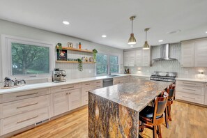 A modern kitchen with a large island, wooden cabinets, and a coffee machine.