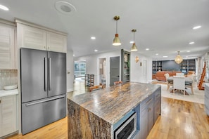 A modern kitchen with a large island, stainless steel appliances, and pendant lighting. - The Spartan Ranch (East Lansing)