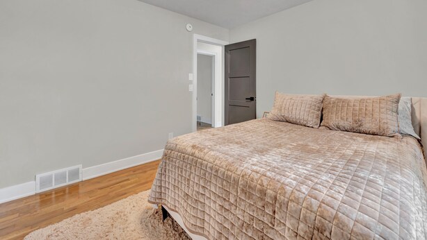 A bedroom with a bed, a door, and a white wall. - The Spartan Ranch (East Lansing)