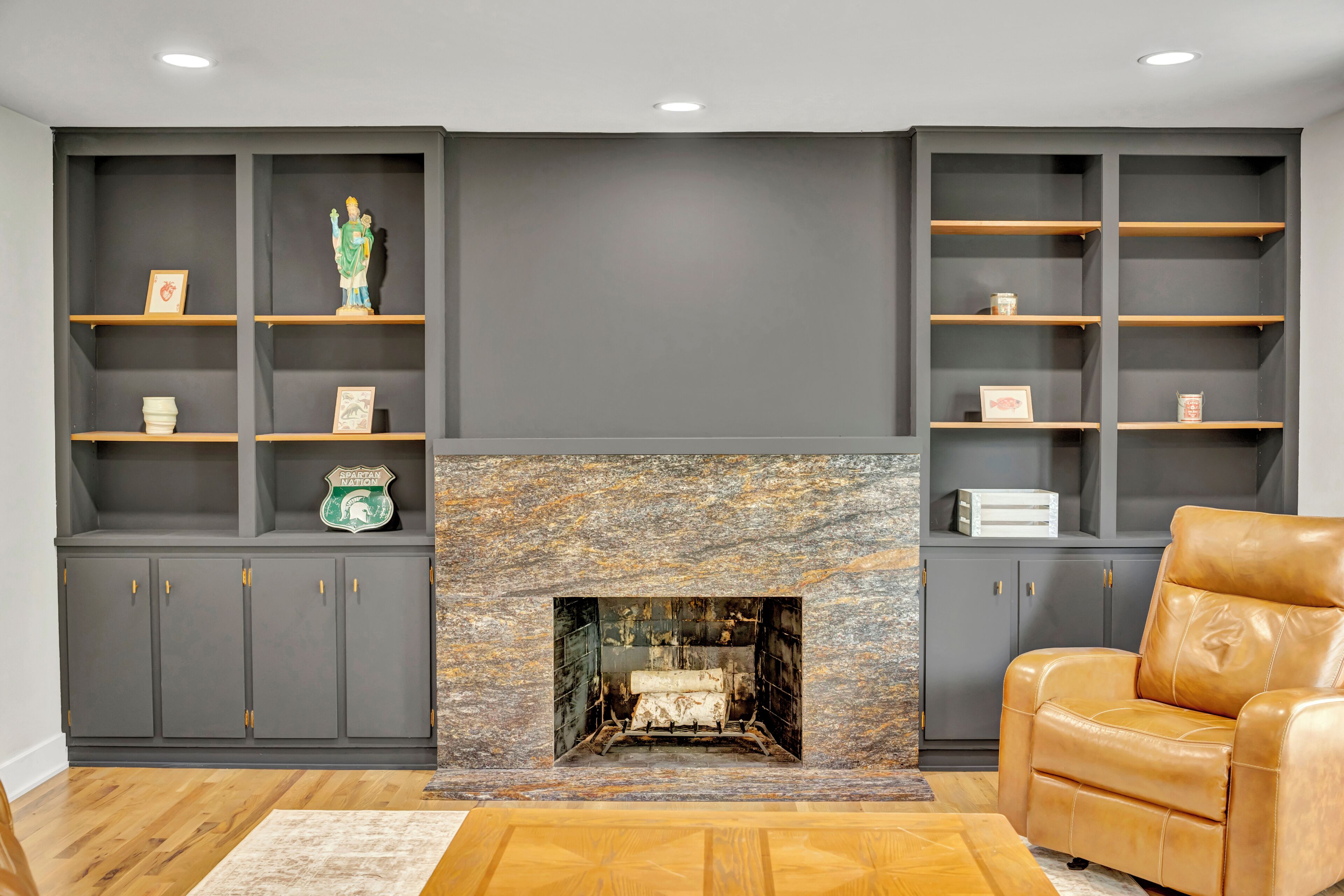A living room with a fireplace, built-in shelving, and a leather armchair.