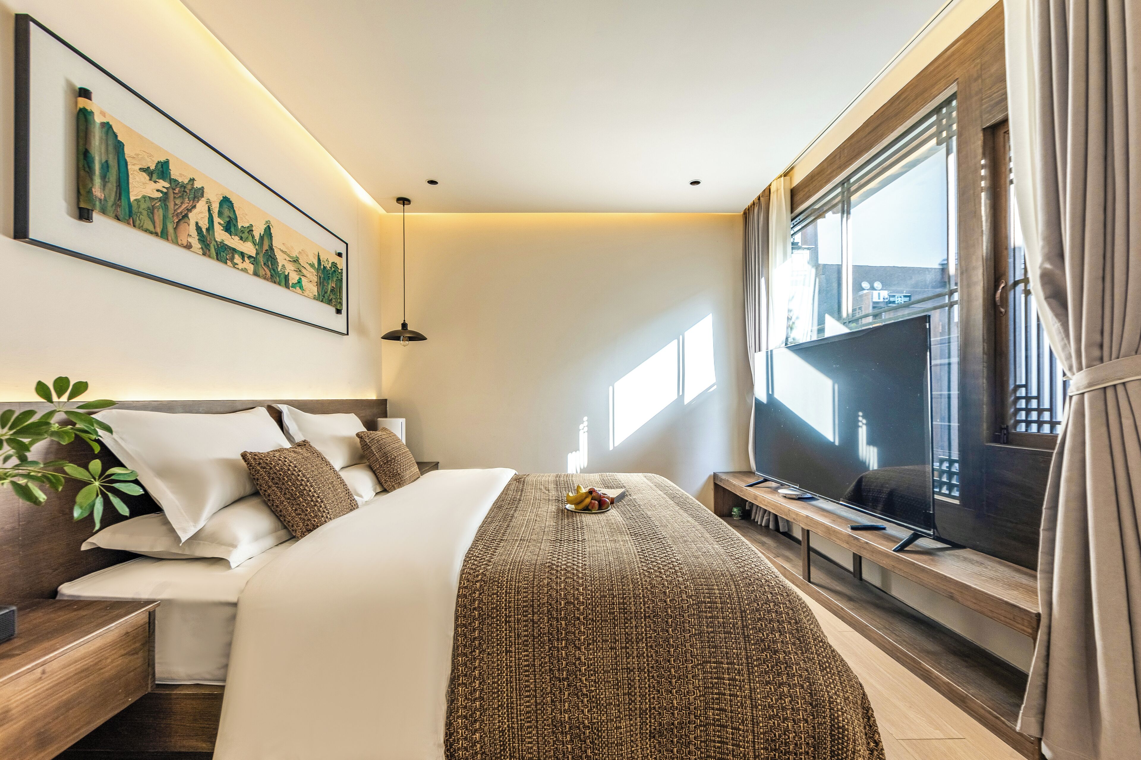 A modern hotel room with a large bed, a flat-screen TV, a painting on the wall, and a window with curtains.