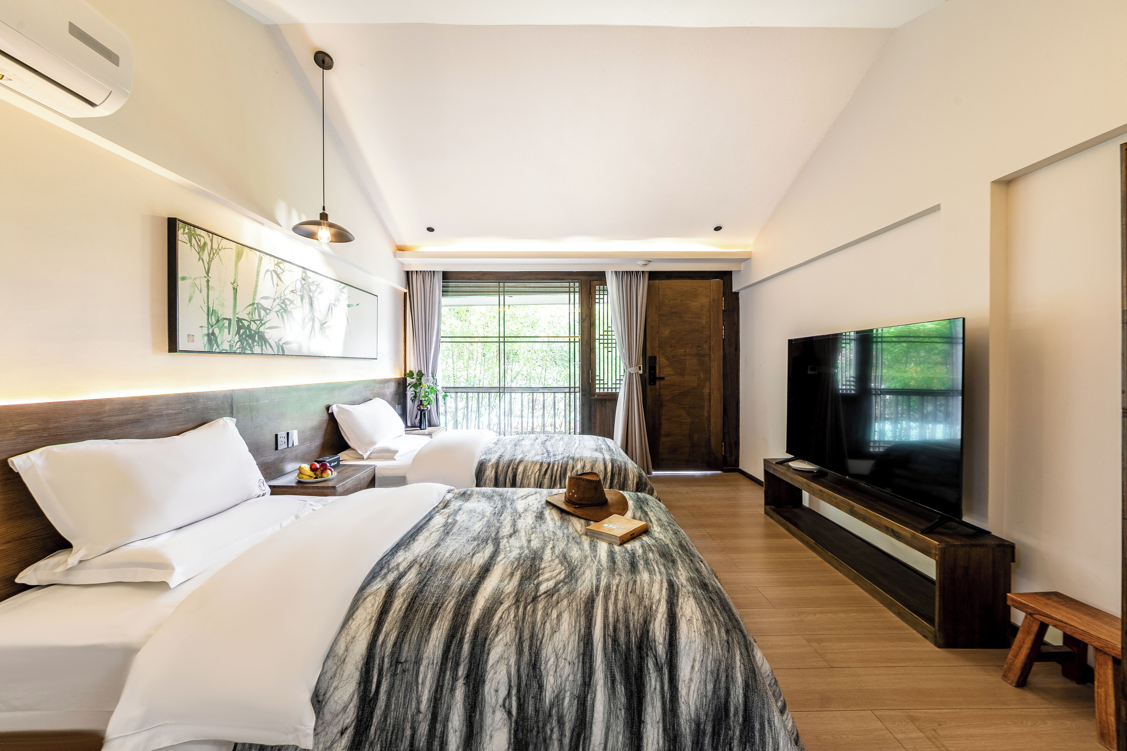 A hotel room with two beds, a television, a dining table, and a large window.