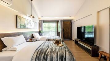 A hotel room with two beds, a television, a dining table, and a large window.