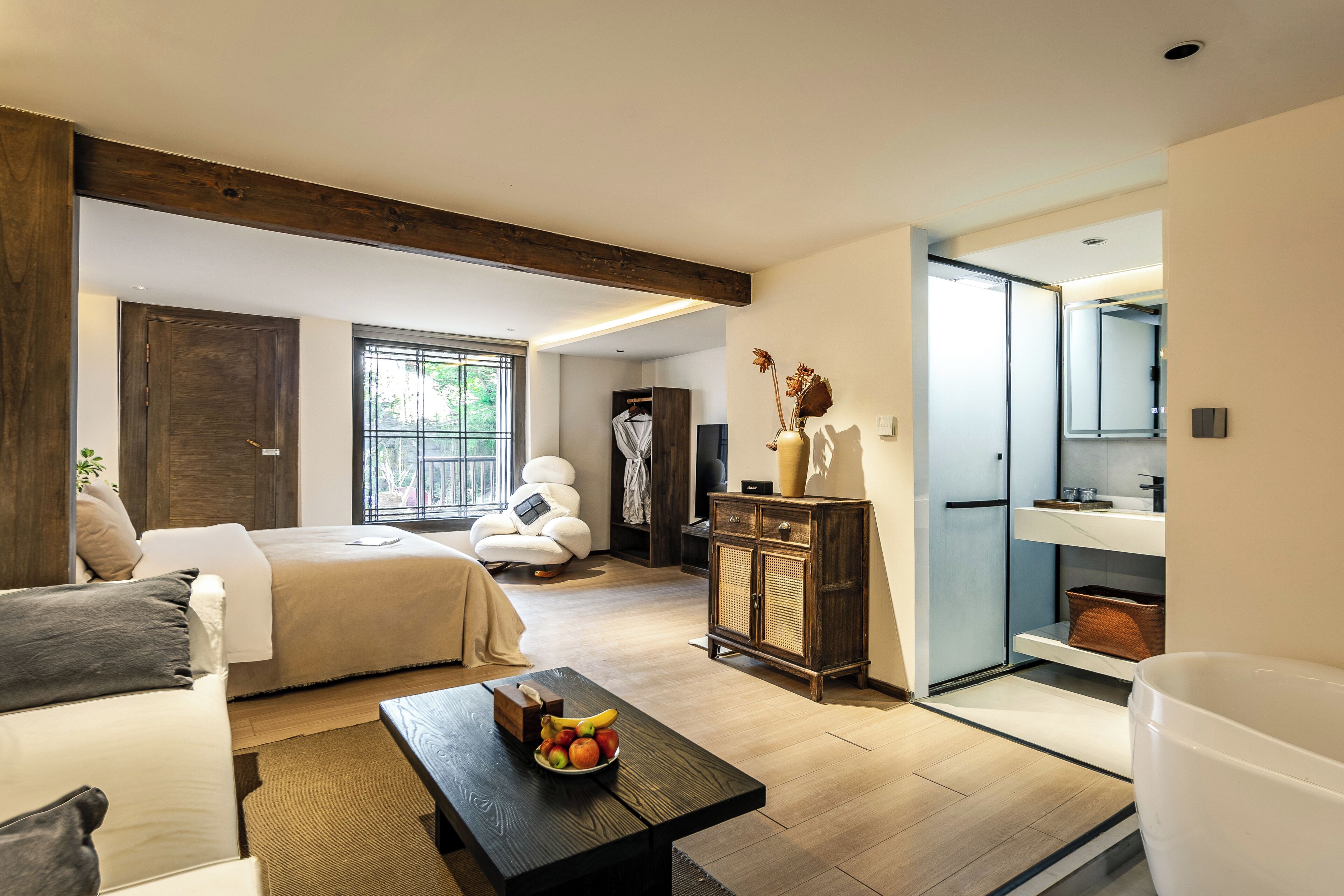 A modern bedroom with a bed, a sitting area with a coffee table, and a bathroom with a mirror.