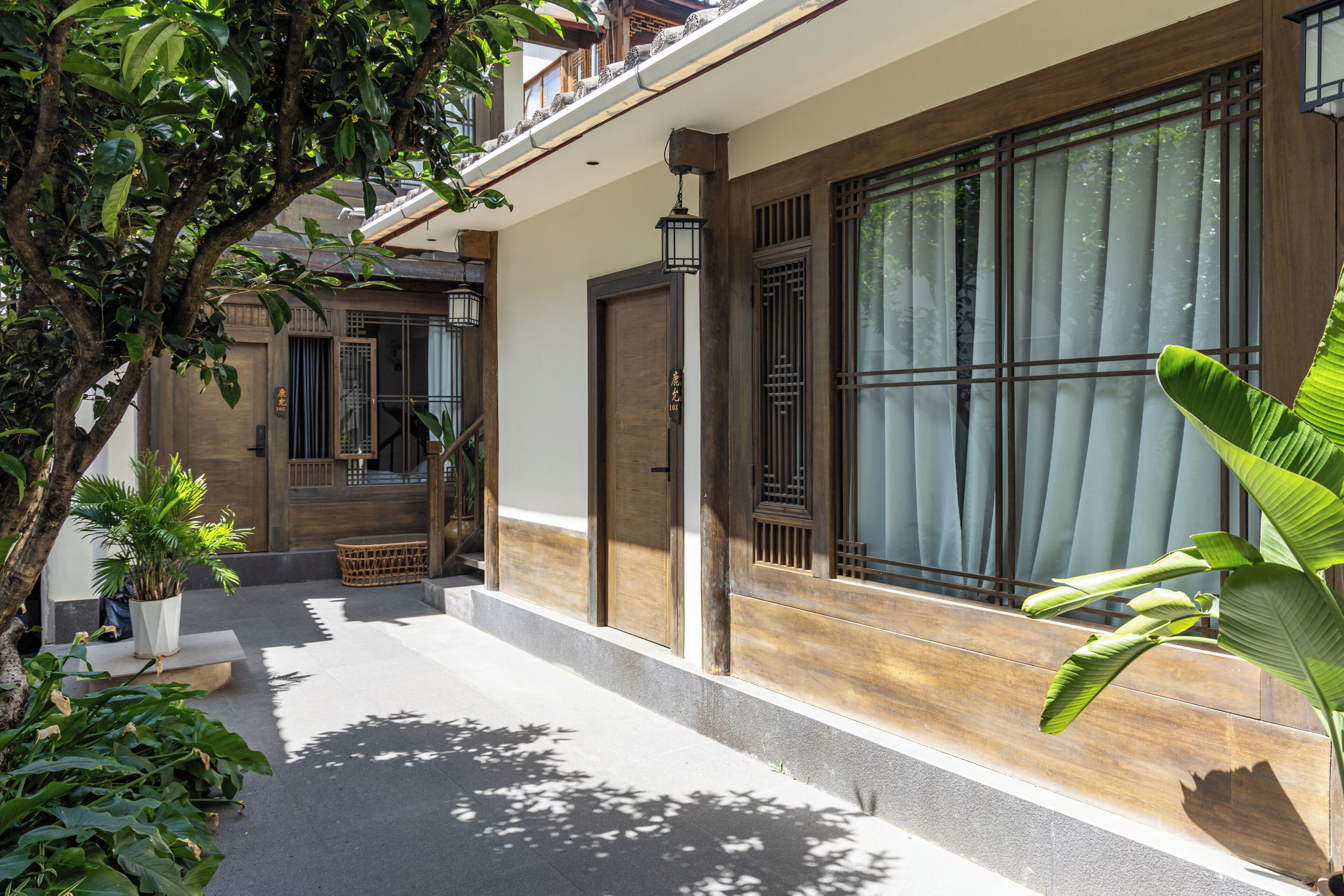 A traditional building with a wooden door, a window with a curtain, and a potted plant.