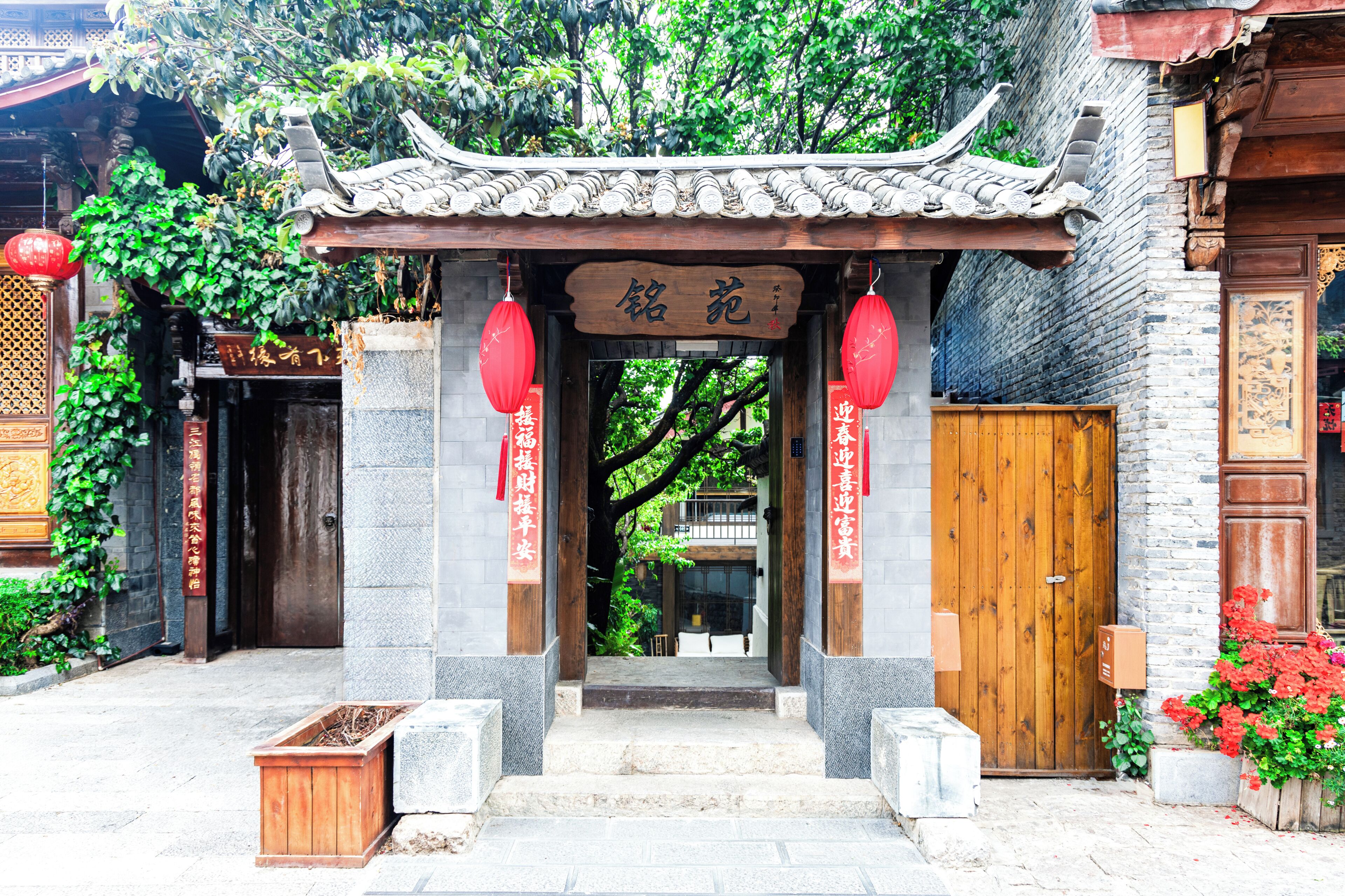 A traditional Chinese gate with a wooden archway, red lanterns, and a sign with Chinese characters.