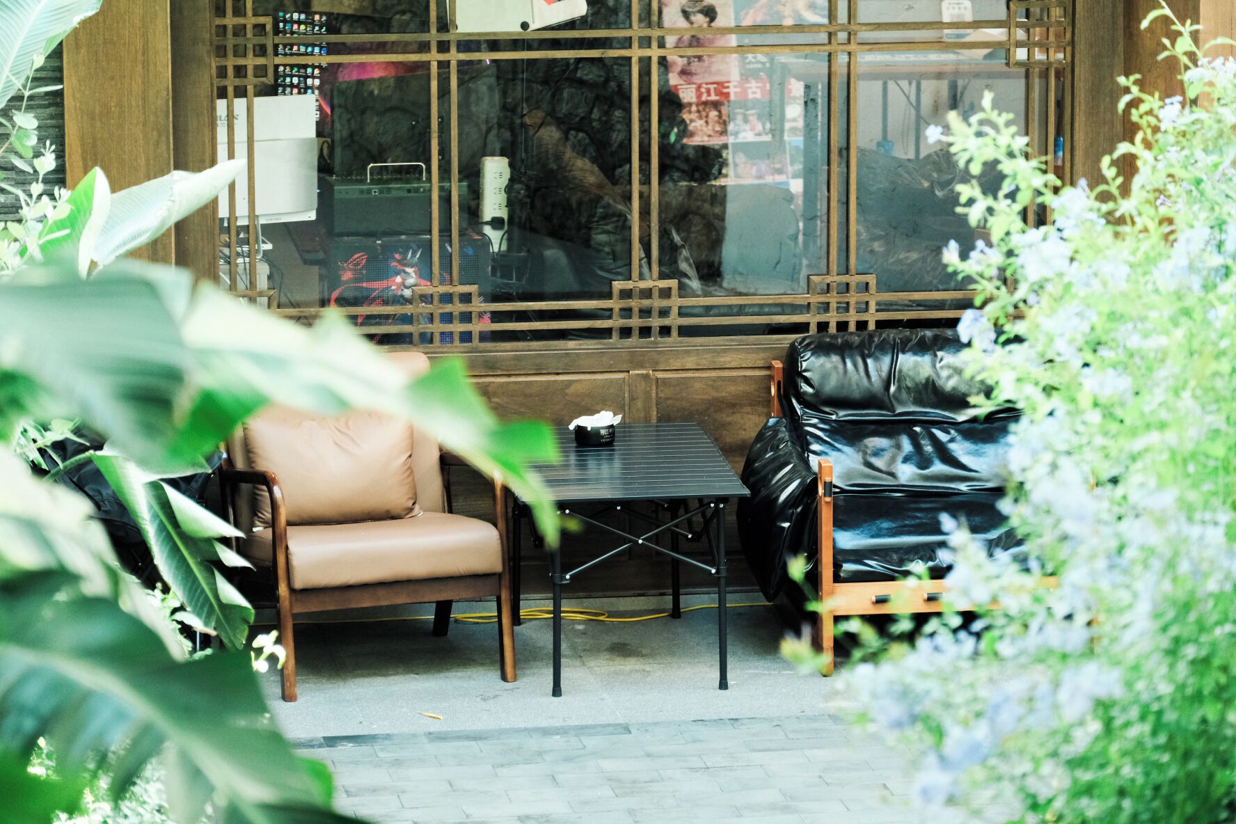 Un coin salon avec un canapé en cuir et une petite table, le tout entouré de verdure.
