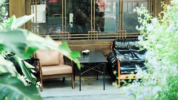 Un coin salon avec un canapé en cuir et une petite table, le tout entouré de verdure.