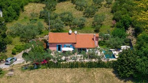 Ein Haus mit Ziegeldach, Satellitenschüsseln, einem Swimmingpool und einem Fahrrad.