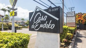A sign for 'Casa de Enedko' with a contact number, surrounded by greenery and a clear sky. - New Listing, Casa De Emdeko, Ocean views,AC (Kailua Kona)