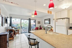 A spacious kitchen with a central island, a dining area with a chair, and a view through the glass door. - New Listing, Casa De Emdeko, Ocean views,AC (Kailua Kona)