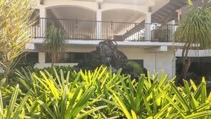A hotel with a central rock feature, balconies, and lush greenery. - New Listing, Casa De Emdeko, Ocean views,AC (Kailua Kona)