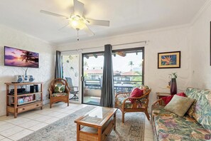 A living room with a ceiling fan, a television, a sofa, and a coffee table. - New Listing, Casa De Emdeko, Ocean views,AC (Kailua Kona)