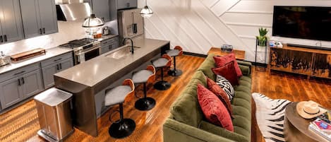 A modern kitchen with a central island, bar stools, and a dining area.