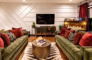 Ein modernes Wohnzimmer mit zwei grünen Sofas, einem runden Couchtisch und einem großen Flachbildfernseher.
