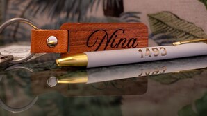 Un bloque de madera con el nombre 'Nina' grabado, un bolígrafo con punta dorada y un llavero con una bolsita de cuero.