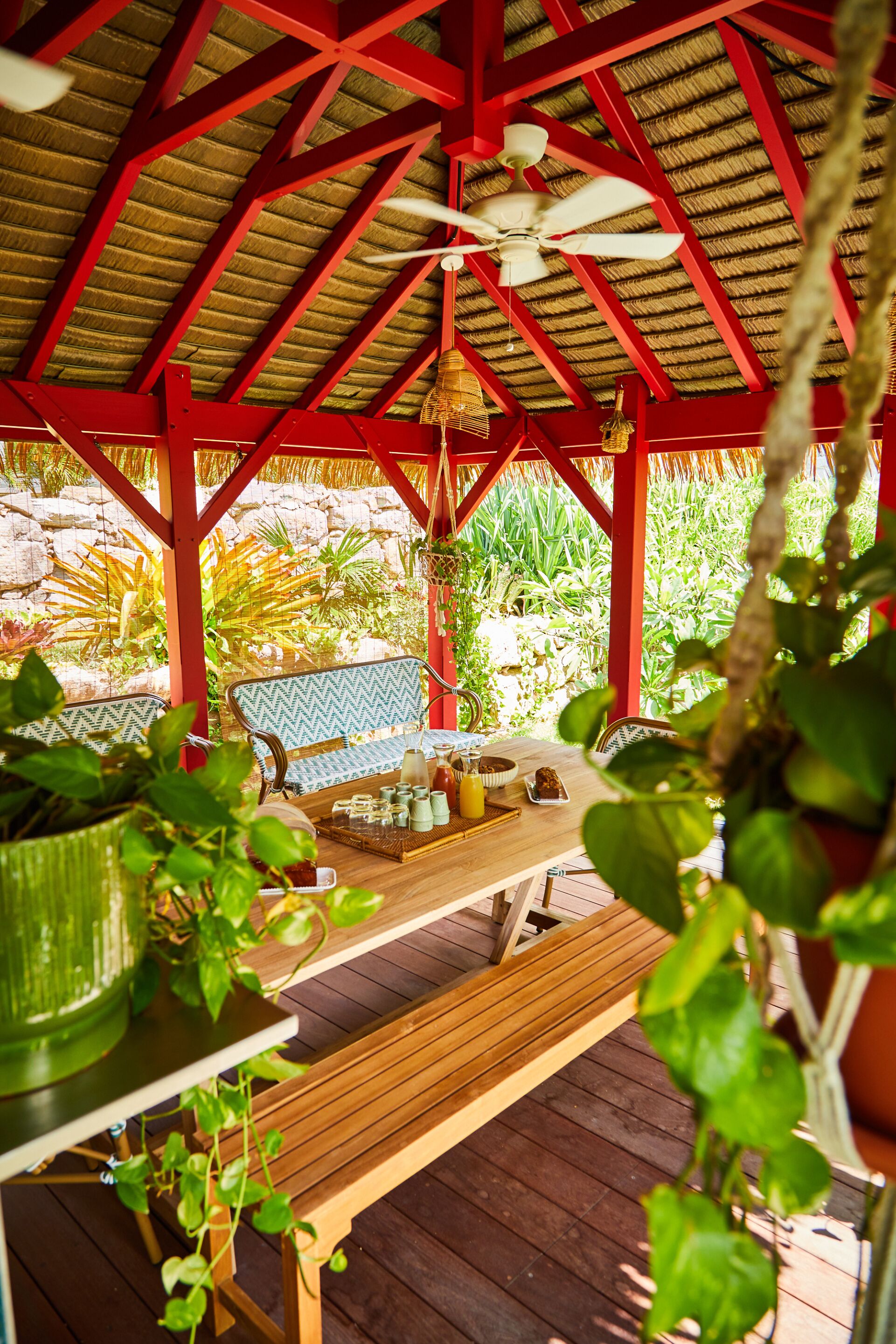 A covered outdoor seating area with wooden furniture and a thatched roof structure.