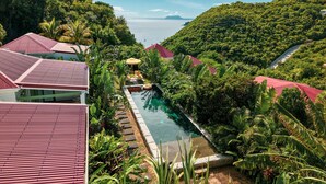 Un resort con piscina rodeado de exuberante vegetación y edificios con techos rojos.