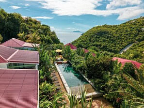 A resort with a swimming pool surrounded by lush greenery and red-roofed buildings.