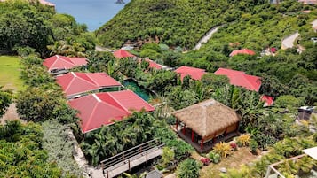 A resort with multiple red-roofed buildings, a thatched-roof structure, and a view of the sea.