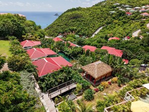 A resort with multiple red-roofed buildings, a thatched-roof structure, and a view of the sea.