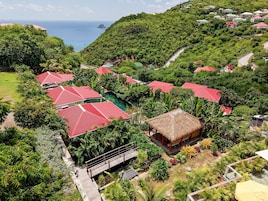A resort with multiple red-roofed buildings, a thatched-roof structure, and a view of the sea.