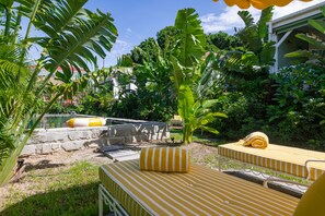 A garden with a pool, stone walls, and striped yellow and white furniture. - 1493 Boutique Hotel St Barth (St. Barthelemy)