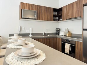 Eine moderne Küche mit Holzausstattung, einer eingebauten Mikrowelle, einer Kaffeemaschine und einem Toaster.