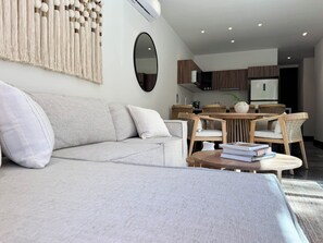 Ein modernes Wohnzimmer mit einer Couch, einem Couchtisch und einem Essbereich mit Stühlen und einem Tisch.