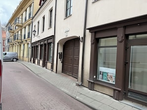 A street view with a building featuring a large brown door, a sign with the number 11, and a poster advertising a spa destination. - Zema11 Old Town Space (Vilnius)